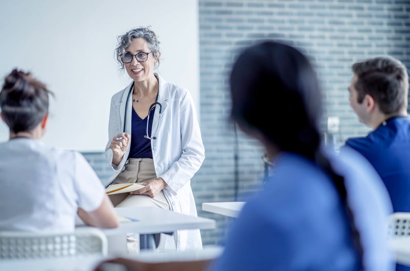 Female professor evaluating medical students with LGI Education in a classroom